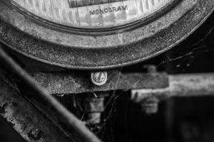 Close-up of dusty vintage car headlight and mounting bracket.
