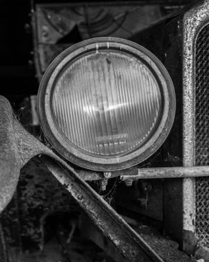 Detailed view of antique car's round glass headlamp.