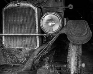 Front grille and headlight detail of classic car with mesh radiator.