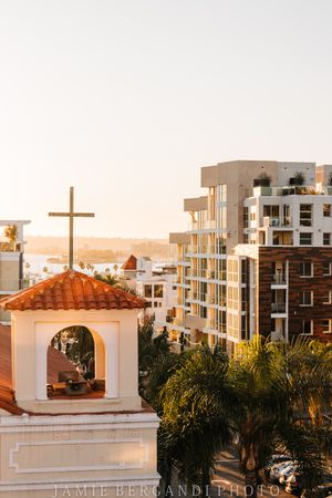 White church steeple with cross against modern apartment buildings during golden hour.