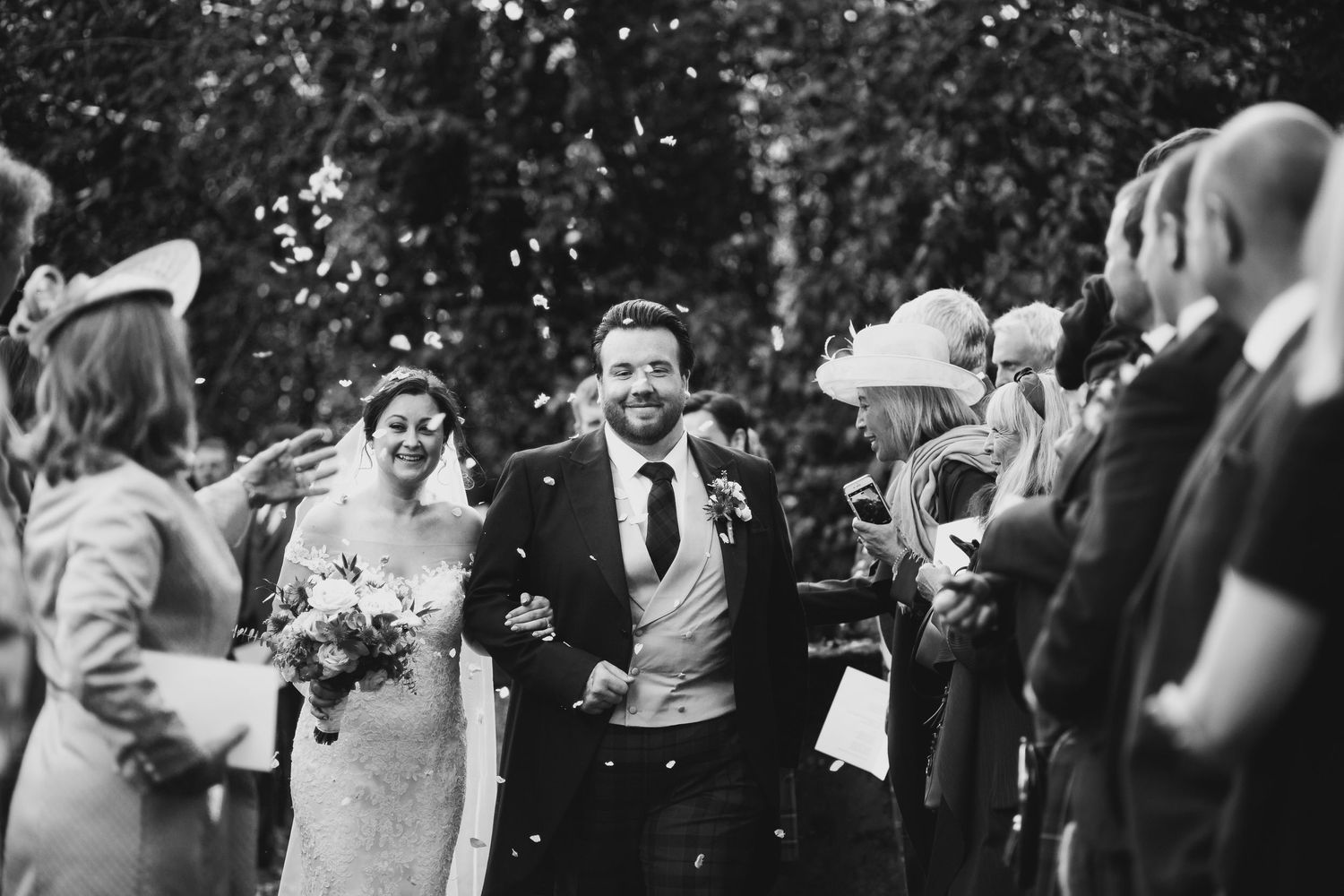 A joyous black and white wedding celebration with guests throwing confetti at the newlyweds.