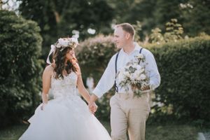 Romantic garden wedding couple in vintage attire share a tender moment among lush greenery and florals.