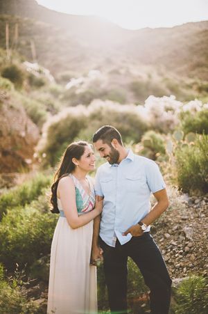 Romantic couple sharing intimate moment in desert mountain landscape during golden hour.
