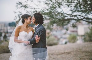 Romantic hilltop wedding portrait overlooking city with bride in strapless gown.