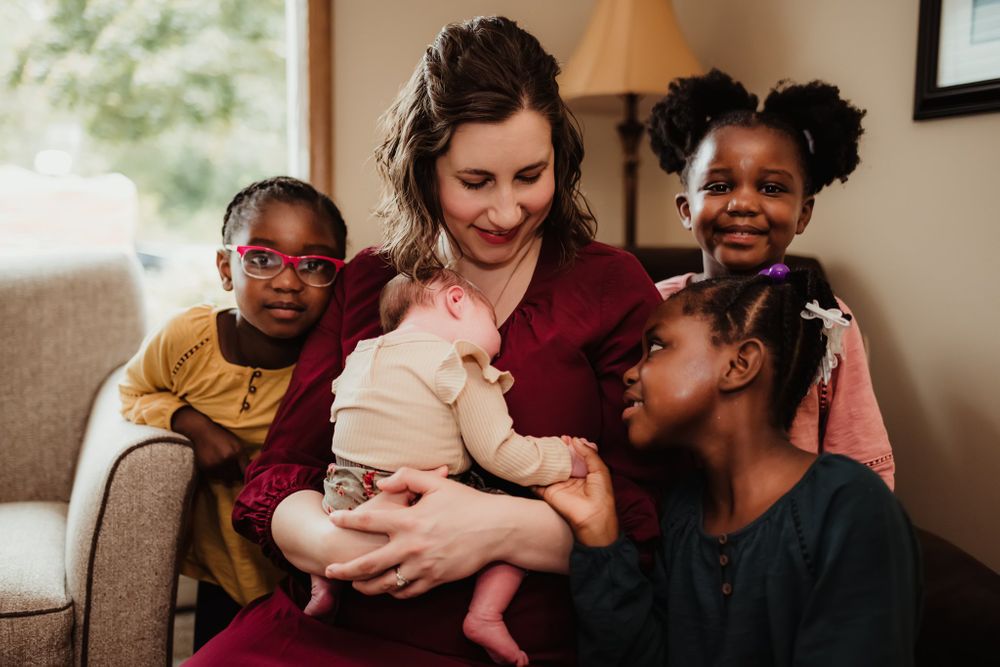 A heartwarming moment as a group gathers around a newborn baby on a comfortable couch.
