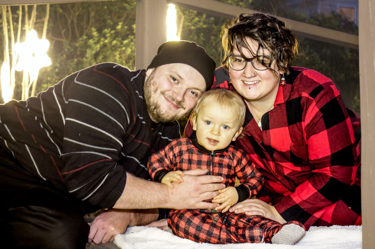 Cozy indoor family portrait with three people in casual winter clothing.