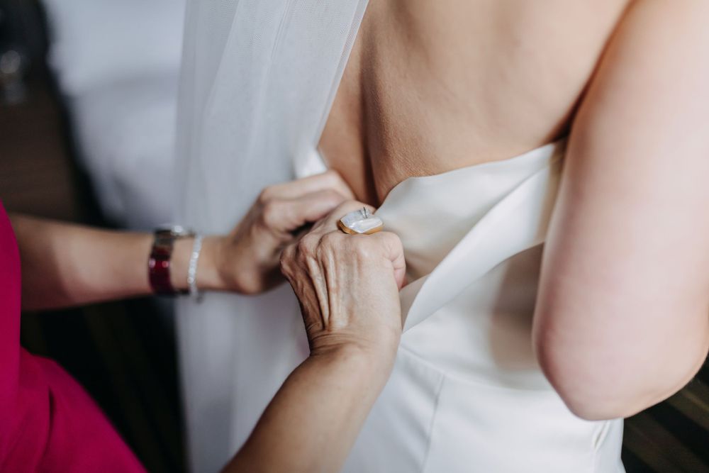Close-up of hands adjusting a white wedding dress.