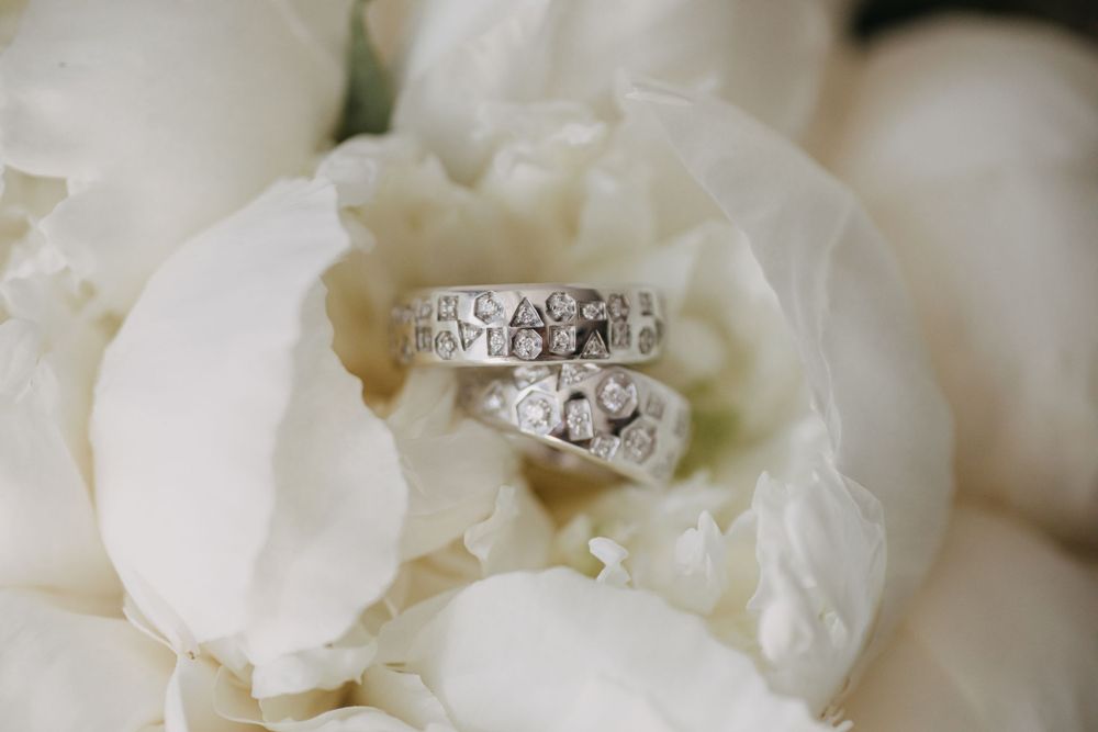 Diamond wedding rings nestled in white peony petals.