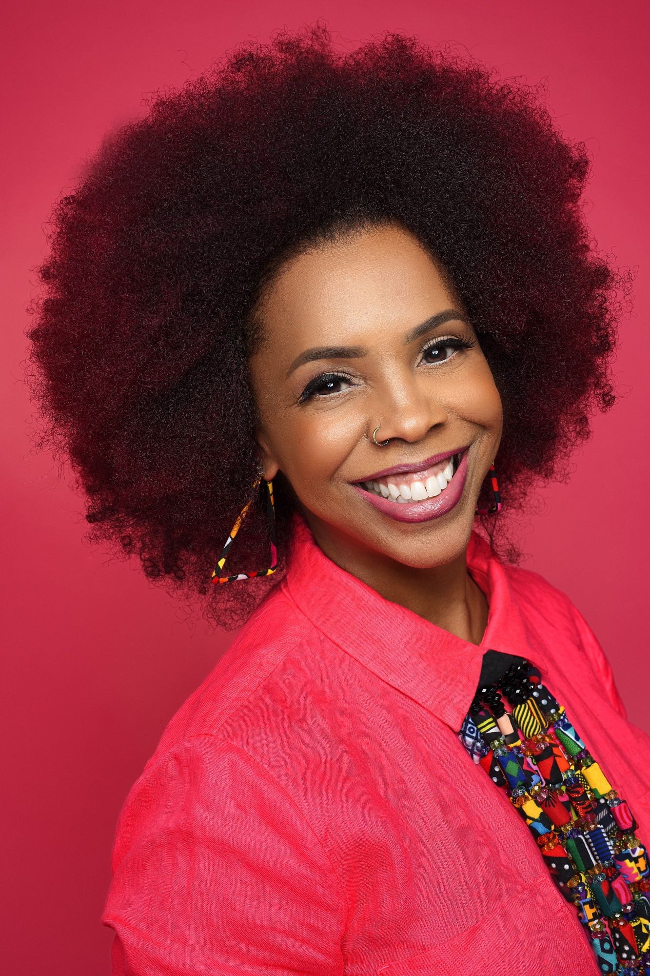 A black female with an afro, confidently poses during a business professional photoshoot, showcasing her natural hair.