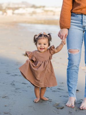 One year old walking with mom on beach in Dana Point