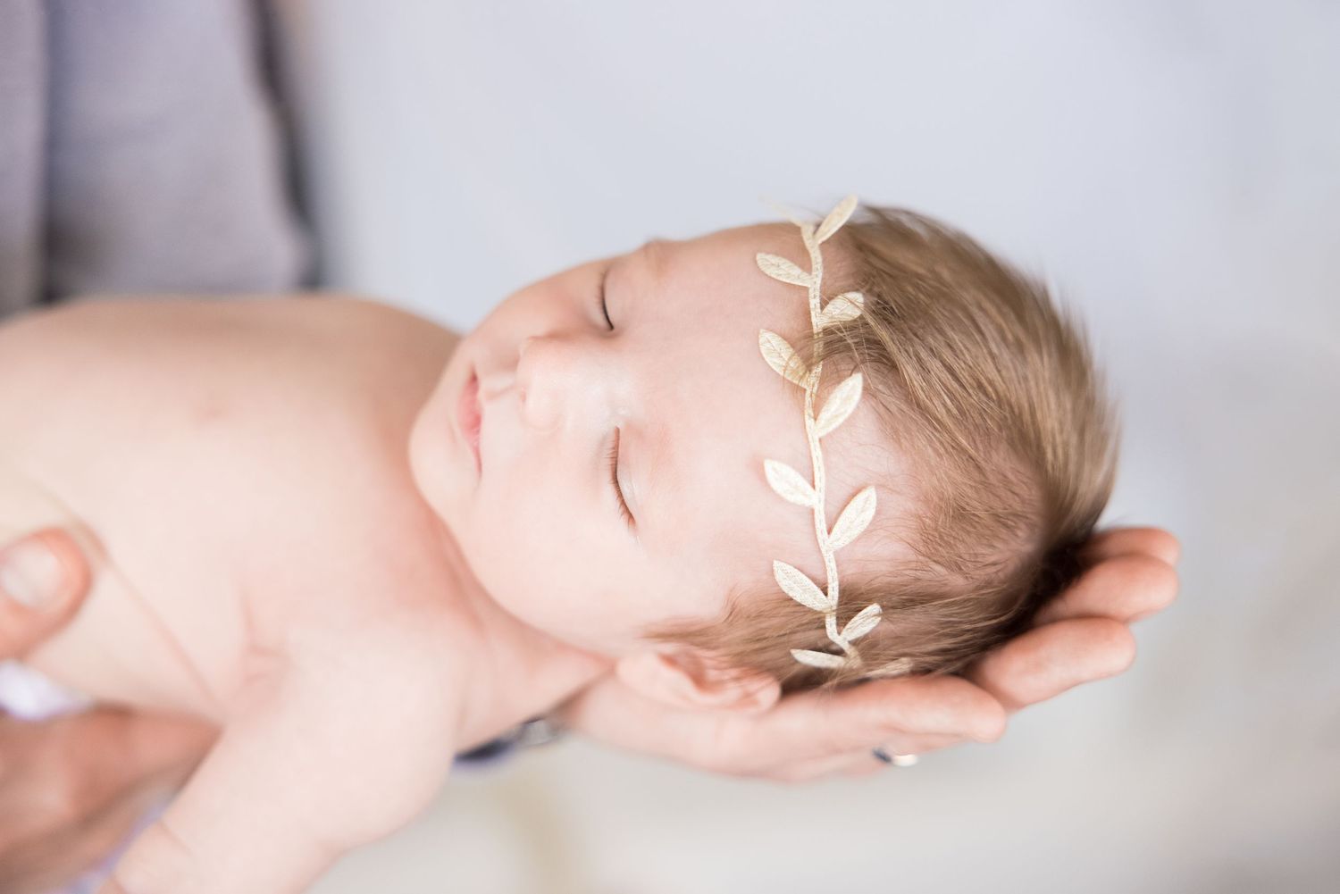 infant with headband being held in father's palm