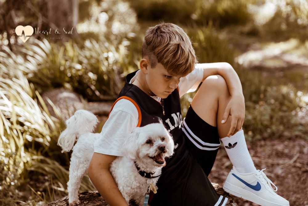 boy holding a white dog sitting on ground