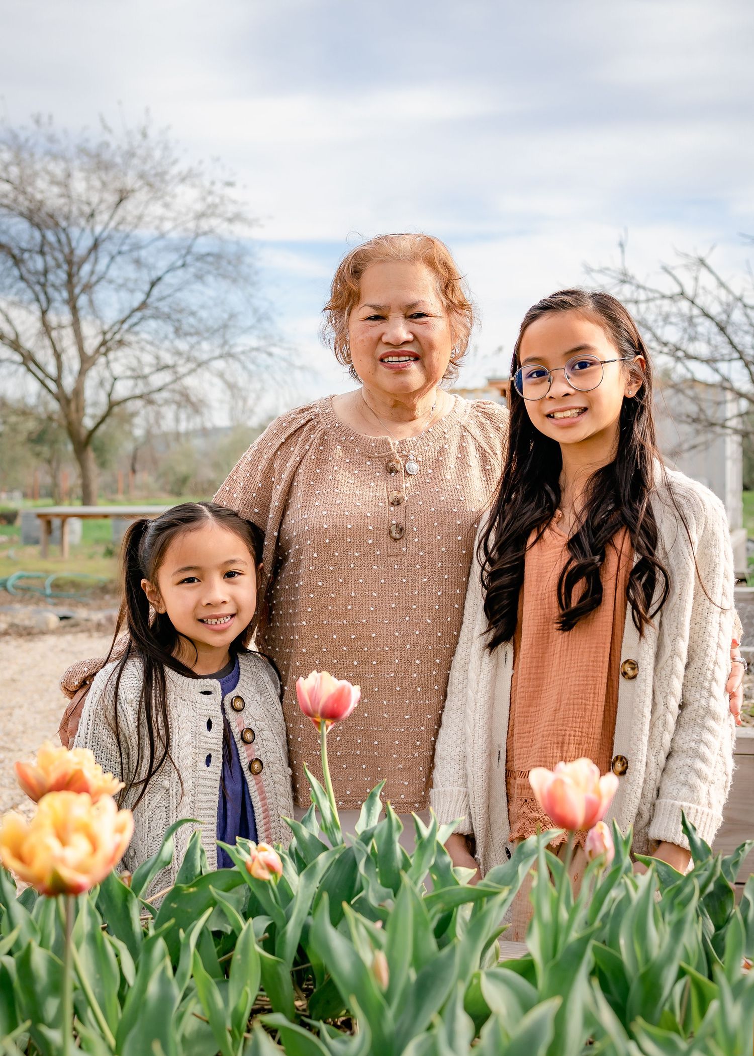 Grandma smiles with granddaugters in front of tulips at Soul Food Farm in Vacaville, CA