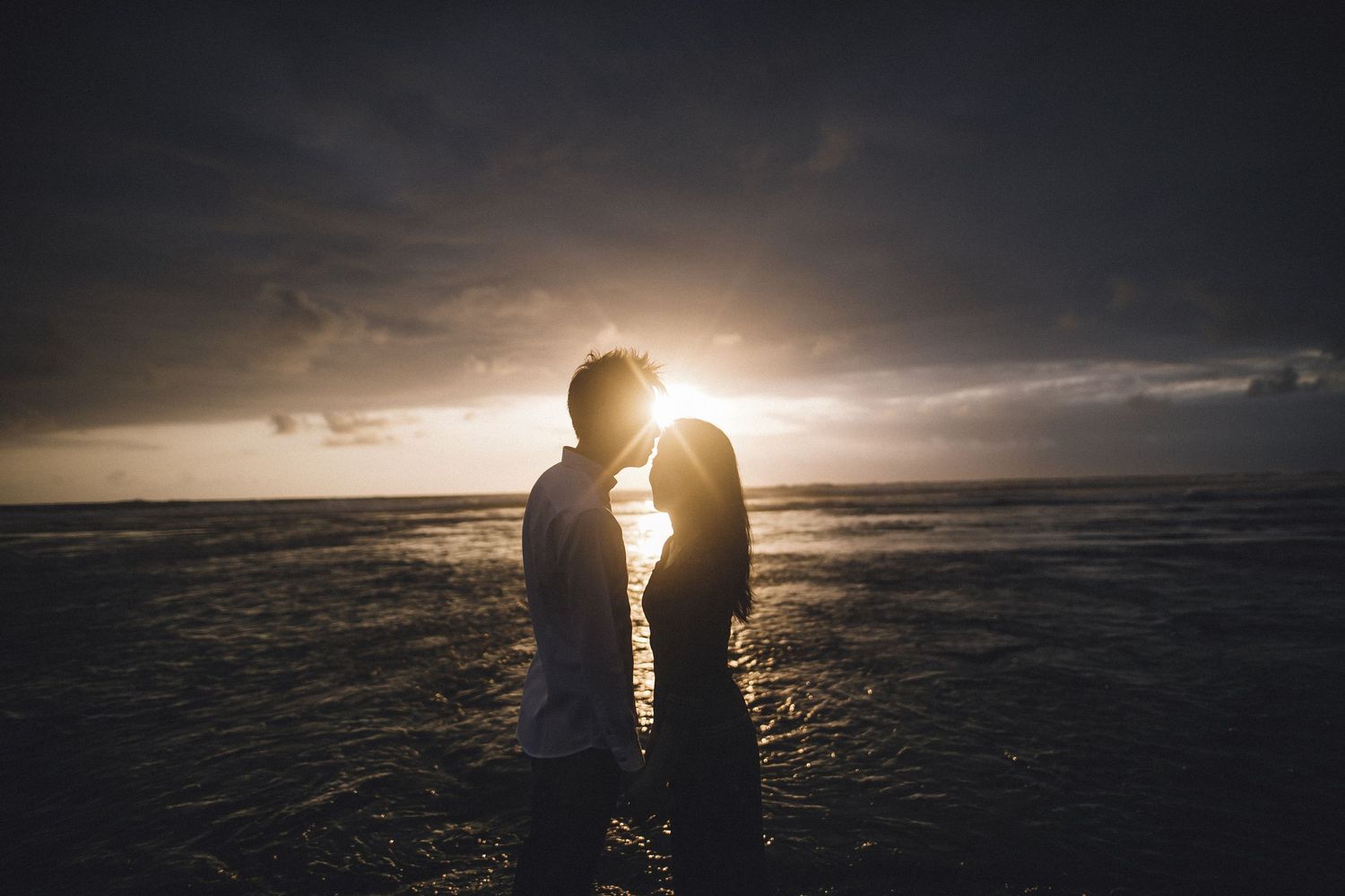 Silhouetted figures standing together against dramatic sunset sky.
