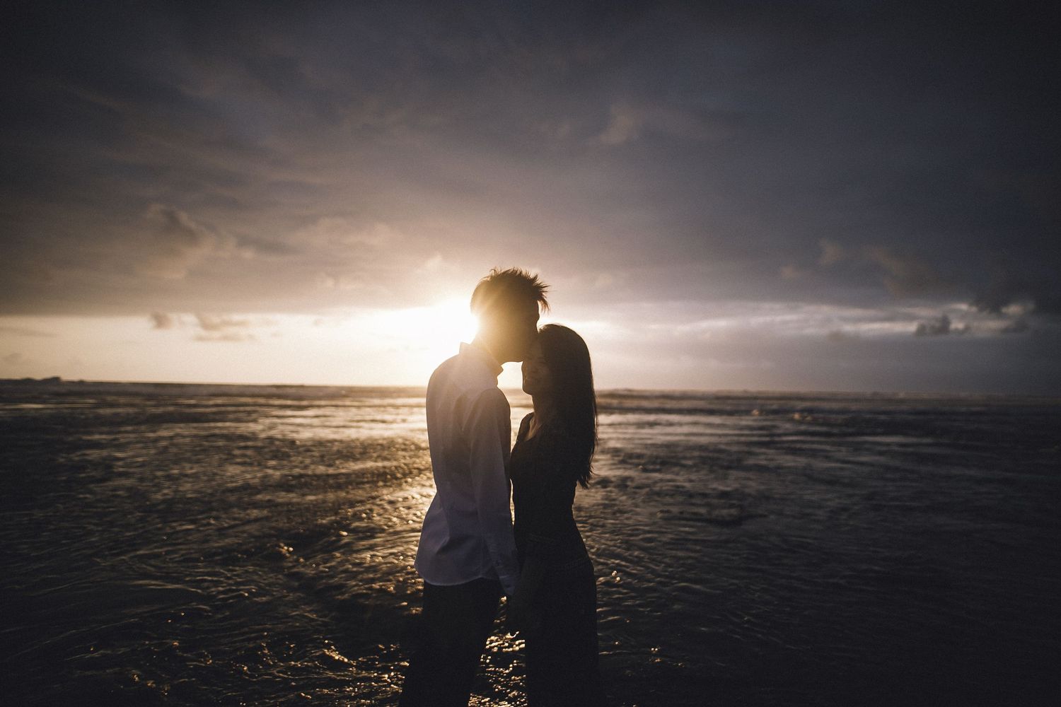 Dramatic coastal sunset scene with couple in silhouette.