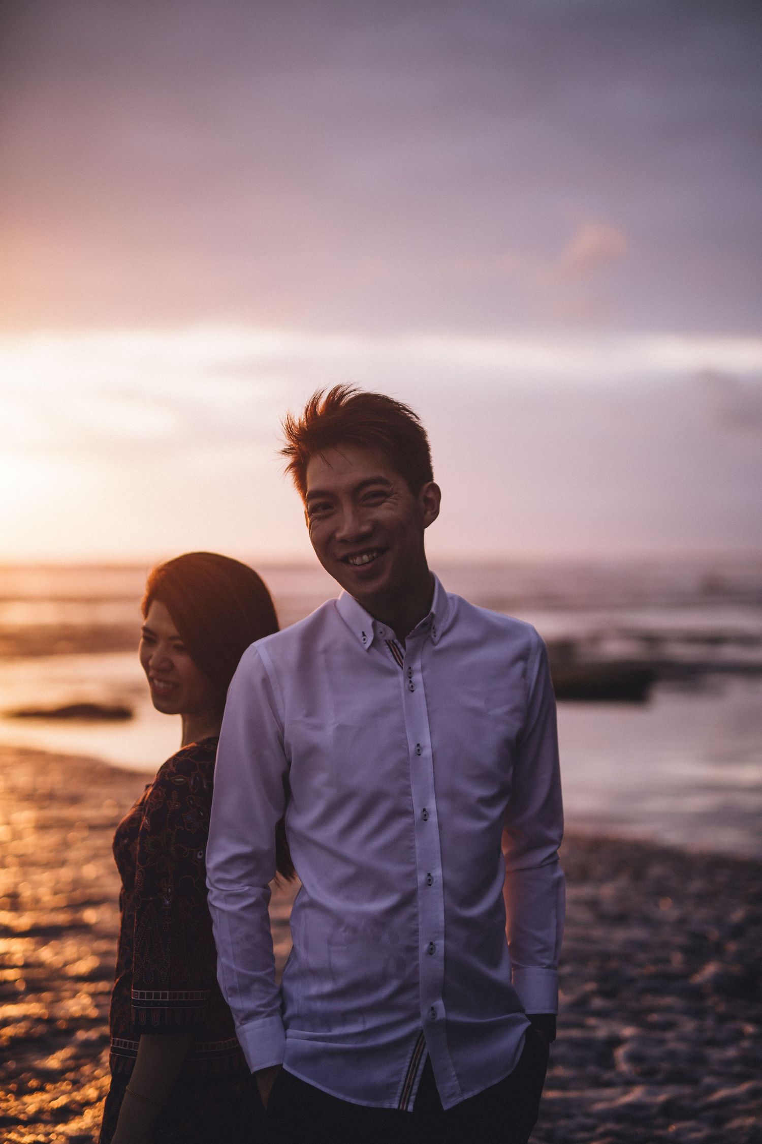Couple enjoying sunset on beach with warm golden light illuminating the scene.