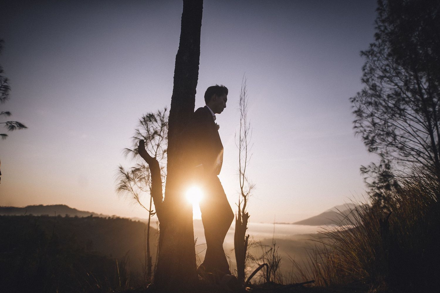 Dramatic silhouettes against a sunset sky with mountains in the distance.