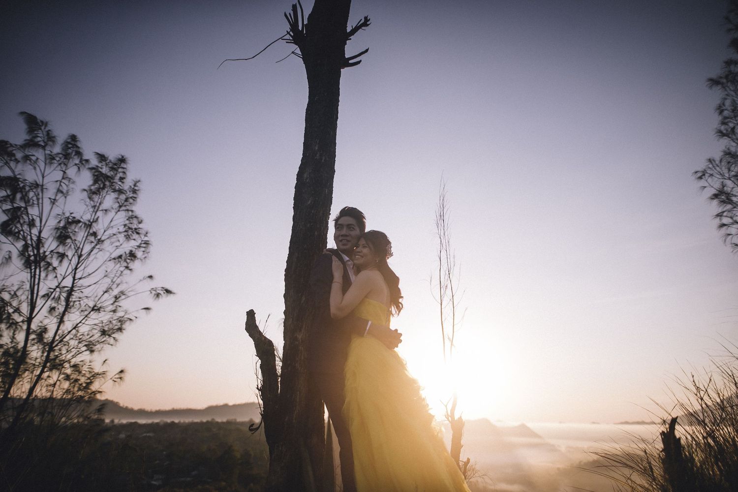 Romantic silhouettes against a setting sun with mountain landscape.
