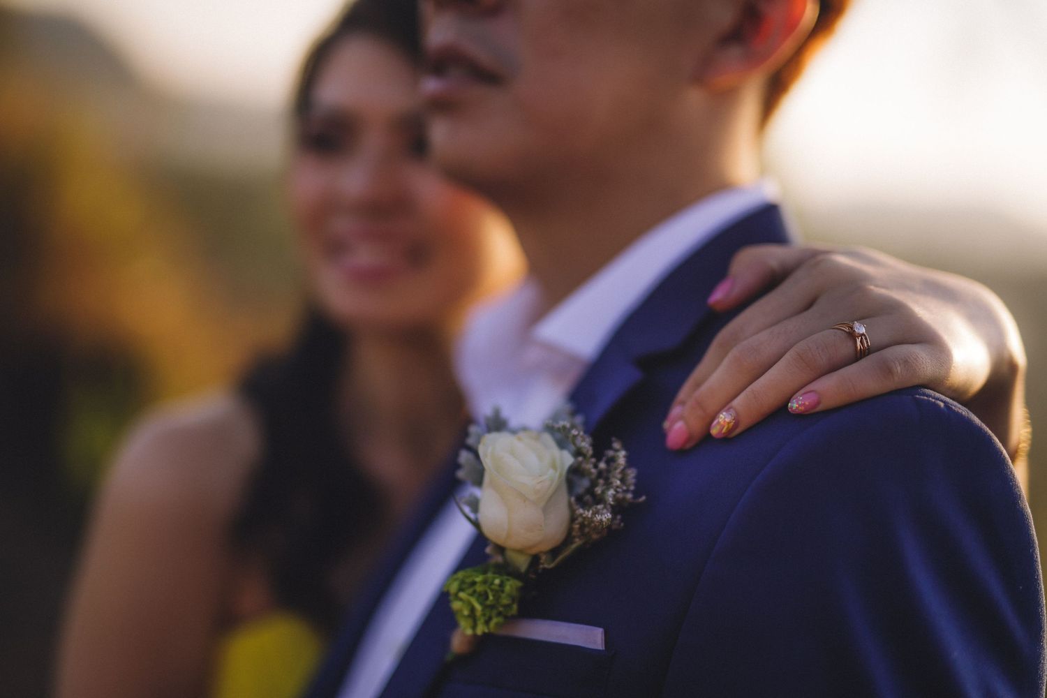 Close-up detail of a white boutonniere on a navy suit jacket during a wedding.