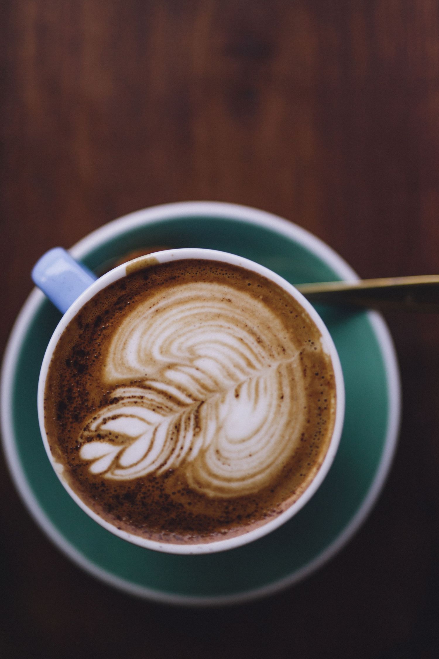 Artistic latte art designs showing progression of a rosetta pattern in multiple coffee cups.