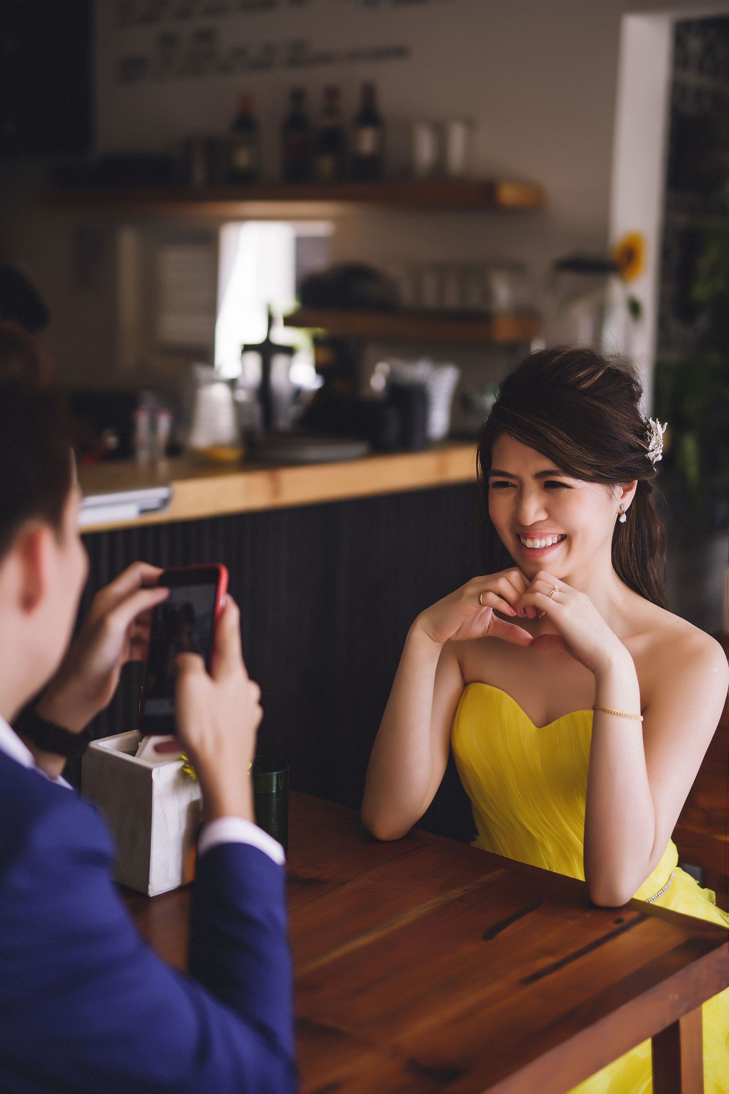 Two people sitting across from each other at a wooden table in a cafe.