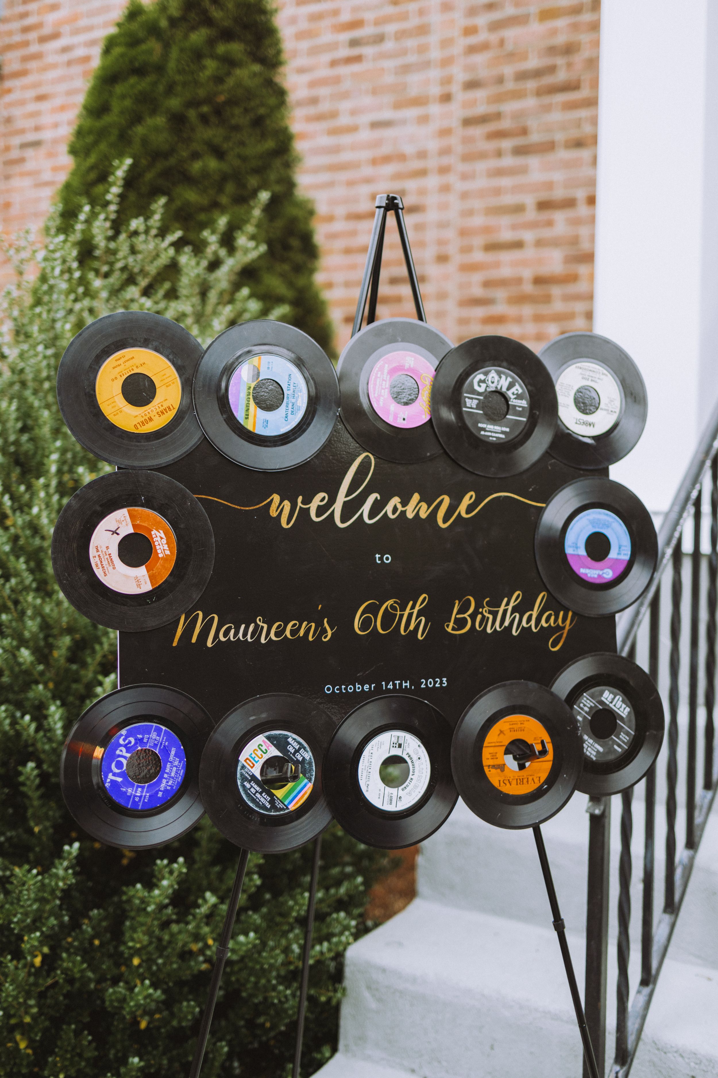 Decorative vinyl record display spelling 'Welcome' with vintage records against brick wall.