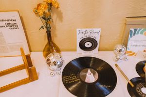 Vinyl records displayed with yellow flowers and disco balls on a decorated table setting.