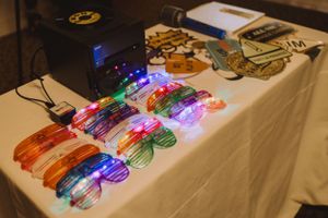 Colorful light-up party sunglasses arranged in rows on a white tablecloth.