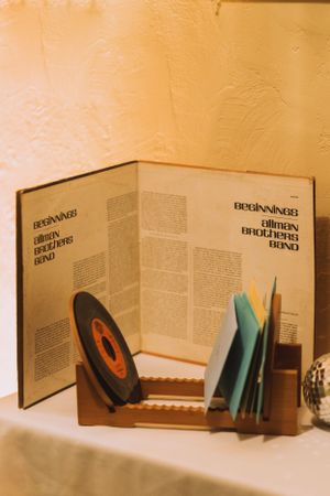 Open book display with vinyl record and blue documents in wooden holder.