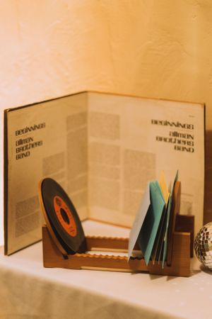 Vintage book display featuring vinyl record and turquoise papers in wooden stand.