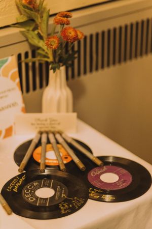 Table setting with vinyl records arranged like a fan with orange flowers in vase.