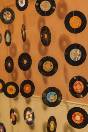 Decorative wall display of vintage vinyl records hanging vertically against an orange background.