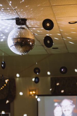 Disco ball and vinyl records hanging from ceiling create retro party atmosphere.