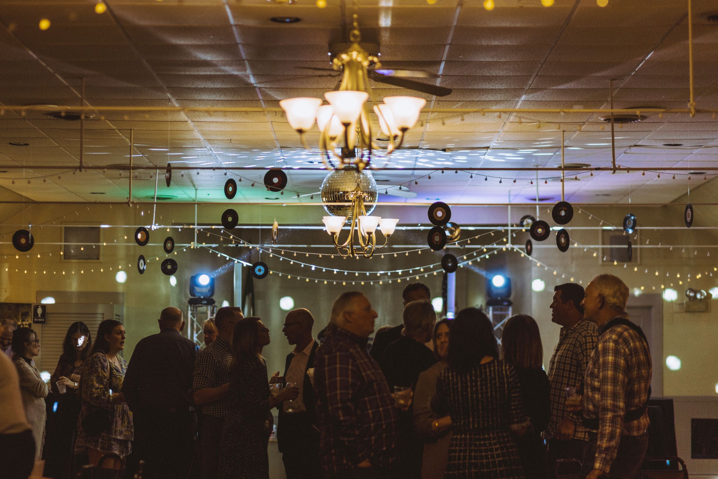 Party venue decorated with hanging vinyl records and string lights creating festive atmosphere.