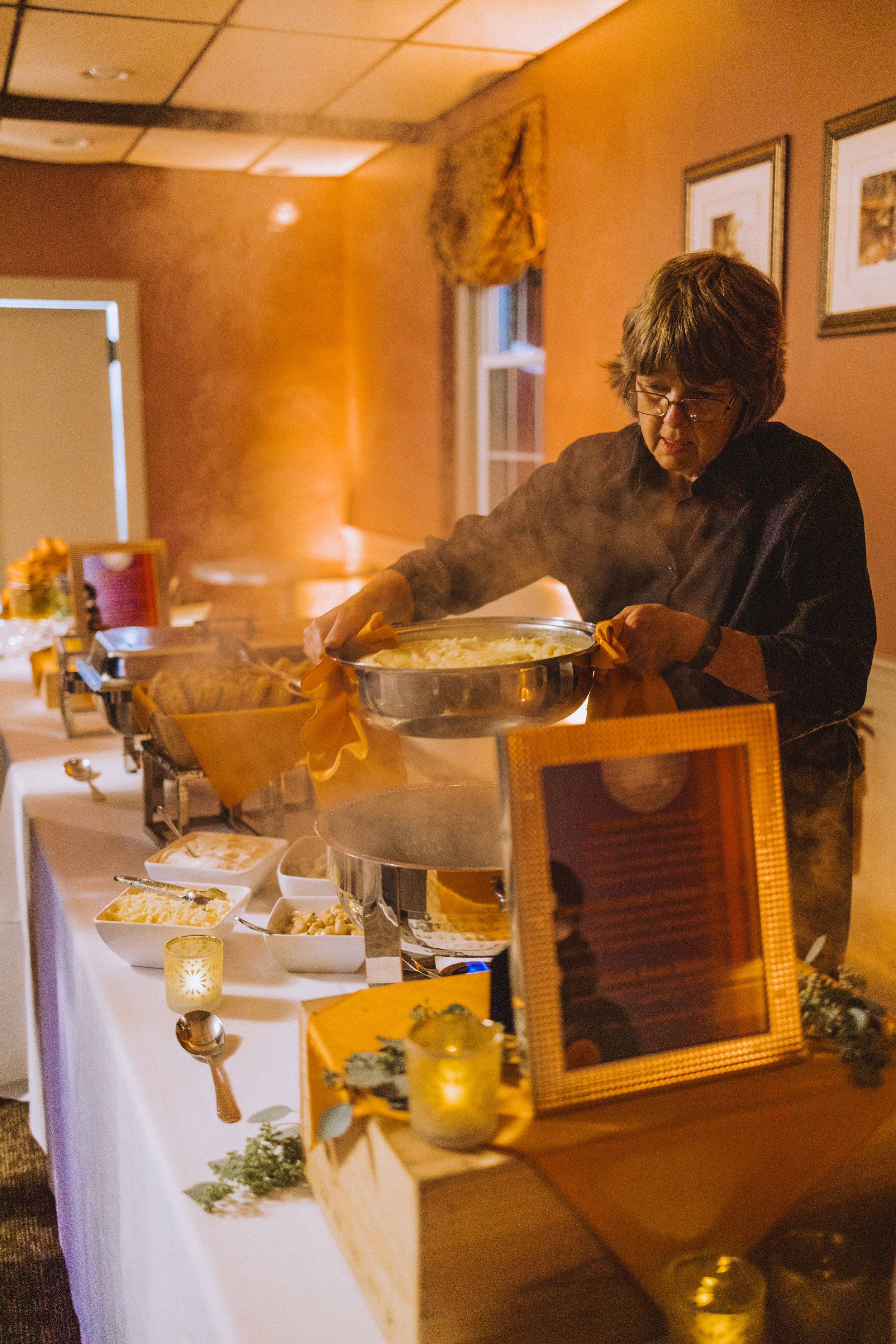 Buffet station with chafing dishes and decorative frame set up for catered event.