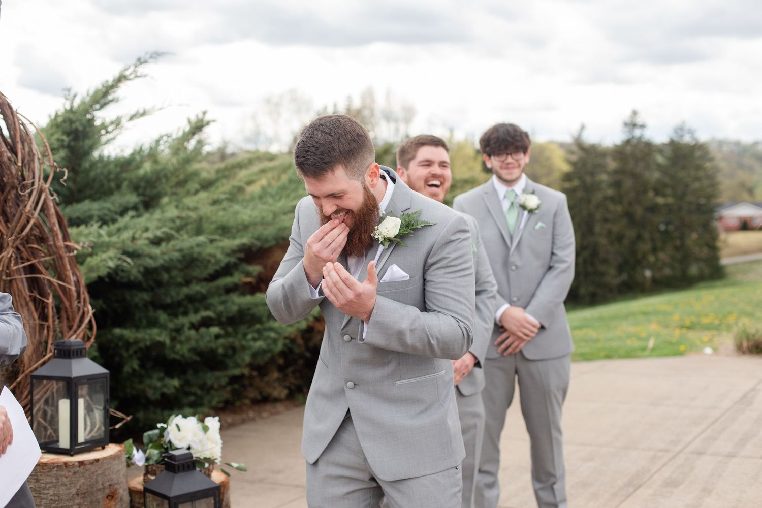 Wedding party members in gray attire interact playfully during outdoor photo session.
