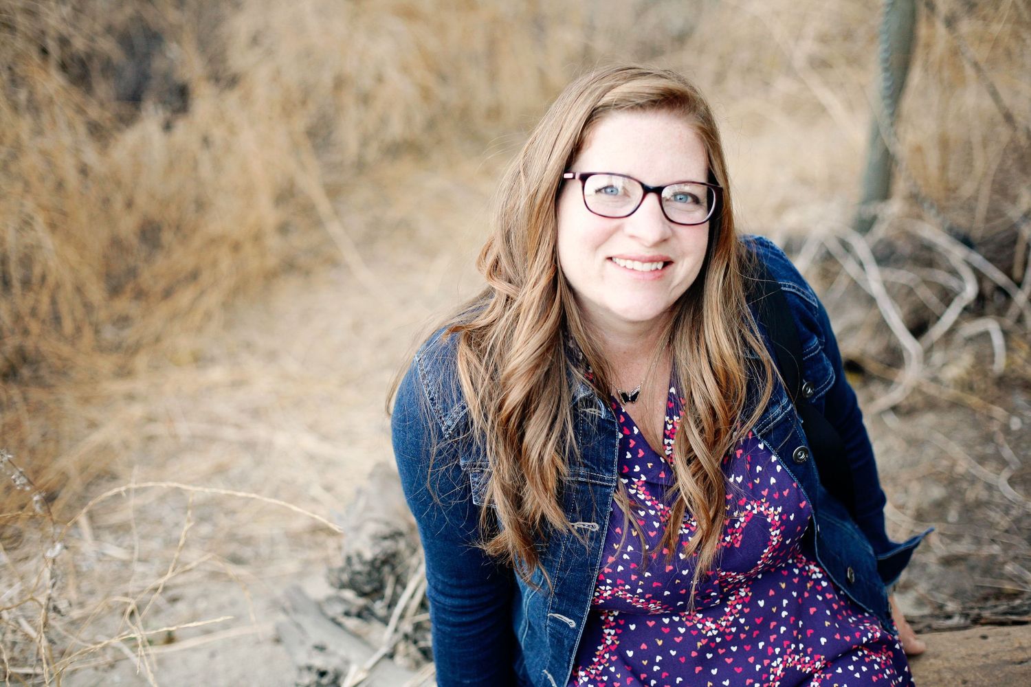 Purple dress and denim jacket outfit captured in natural setting with dried grass.
