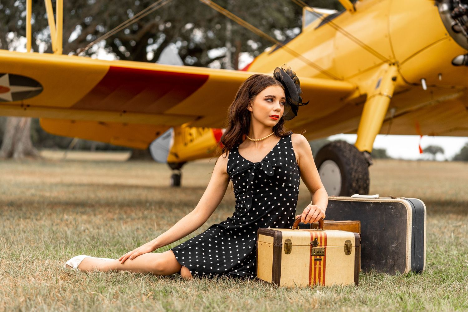 Vintage-styled scene with polka dot dress and retro suitcase near yellow airplane.