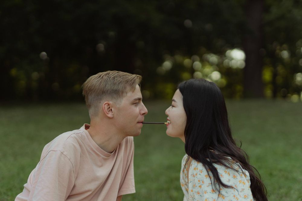A romantic couple sharing an intimate moment on a grassy lawn during golden hour.