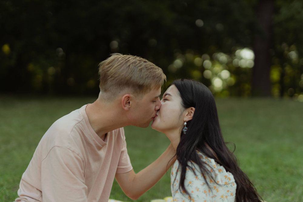 A tender moment shared between a couple during a romantic outdoor picnic.