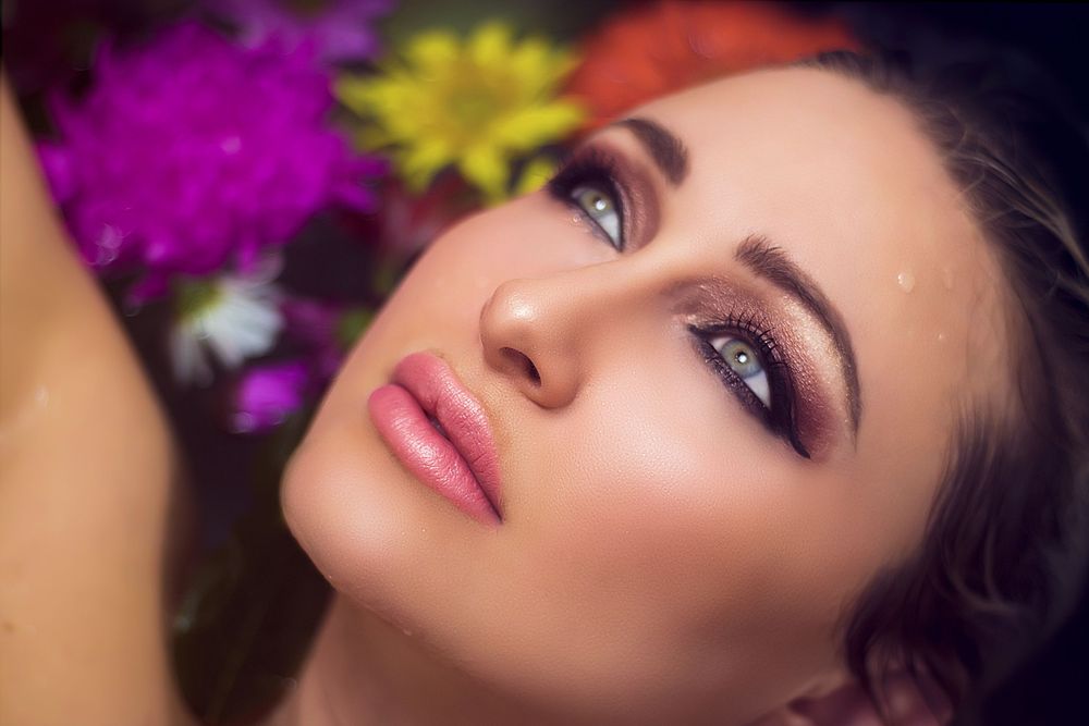 Artistic portrait with pink and yellow flowers creating ethereal mood.