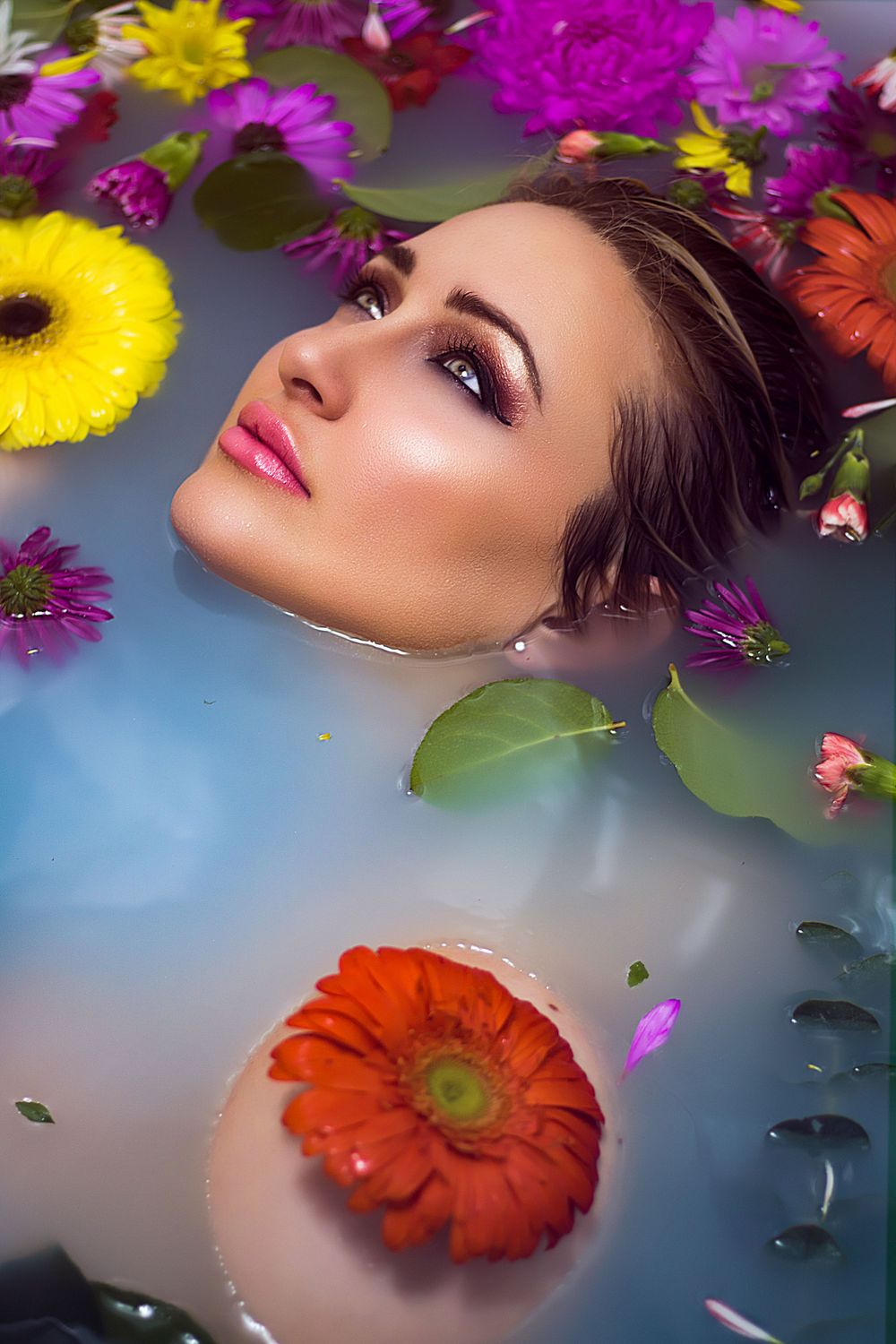 Close up beauty shot with colorful flowers and soft lighting against blue background.