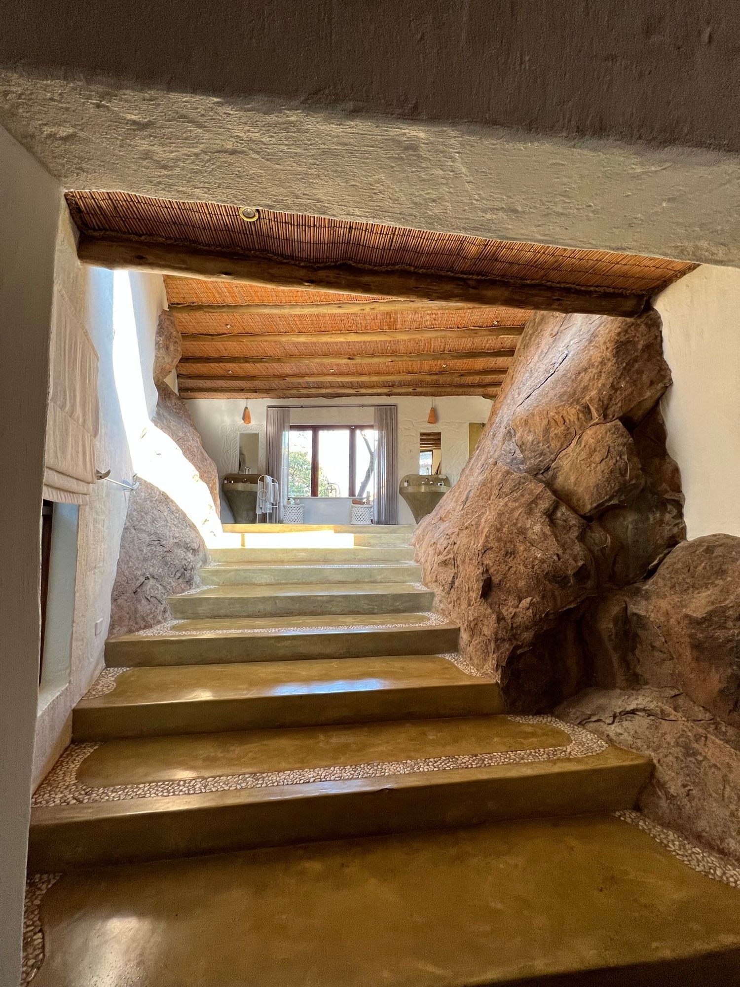 Stone steps leading upwards with rustic wooden beams and white walls in an ancient architectural setting.