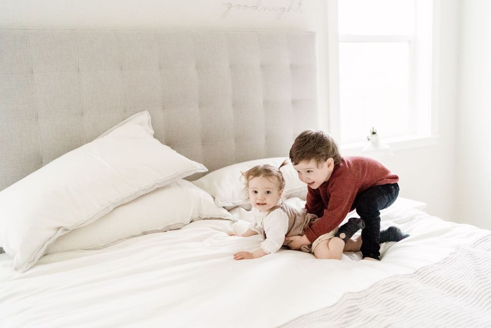 siblings playing on the bed lifestyle family session