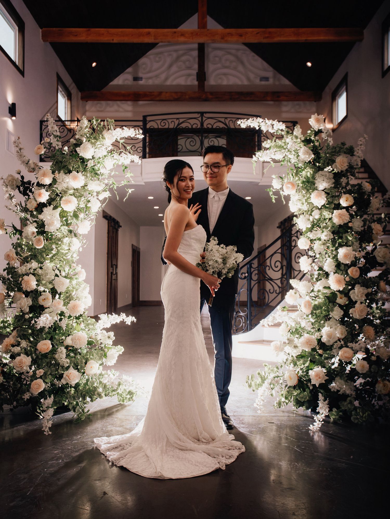 Wedding at Primrose Hill with ivory dress, sage colored flowers and arches, and groom in royal blue suit.
