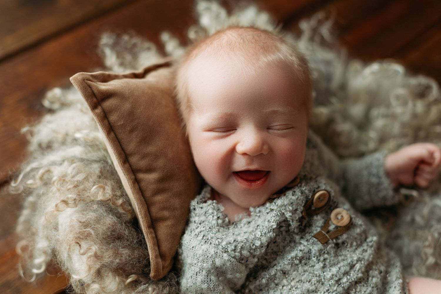 Very smiley newborn boy lying on a pillow. Greenville SC newborn photographer - Easley SC newborn photographer