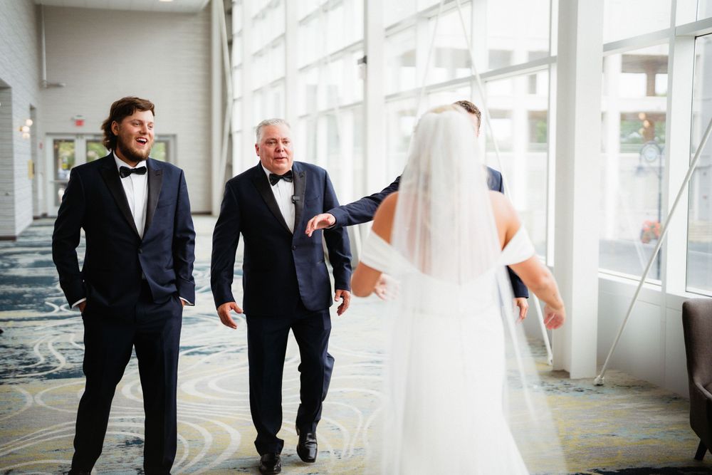 A wedding party shares a candid moment in a sunlit hallway with modern decor.