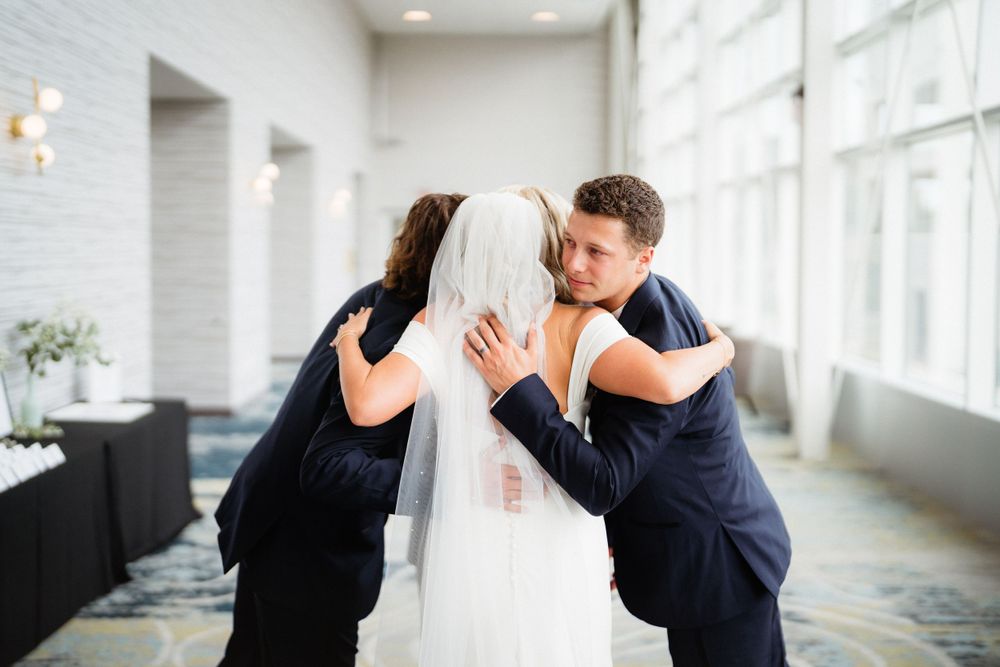 An emotional group embrace during a wedding celebration in a modern venue.