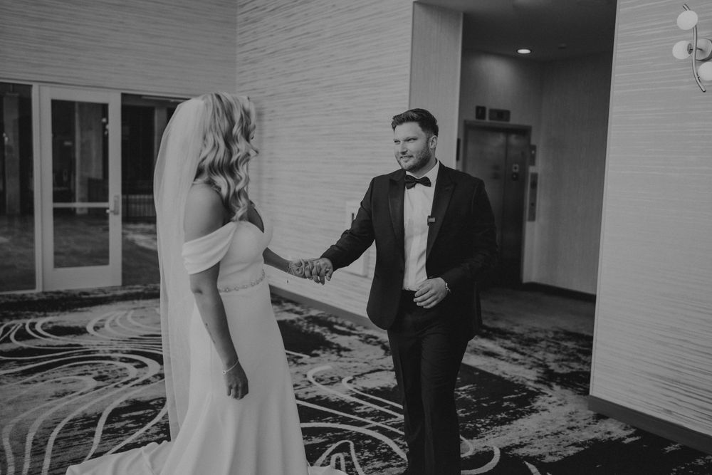 Black and white photo of couple sharing a touching moment in formal attire.