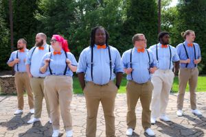 Groomsmen in light blue shirts and suspenders lined up showing casual attire.